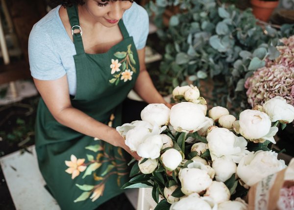Female florist arranging white peony flowers in a shop